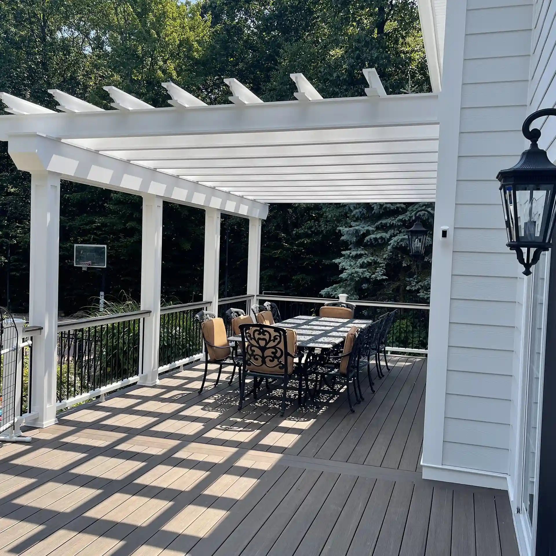 photo of a deck with a white pergola and outdoor furniture