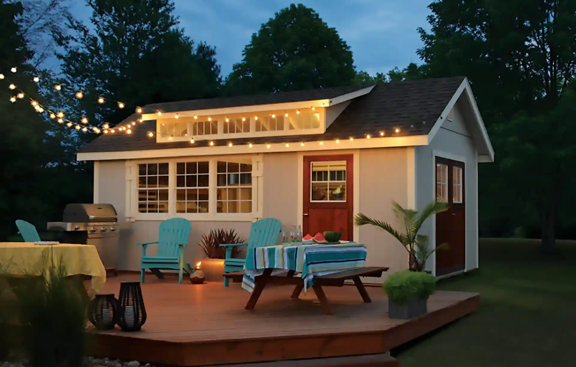 Backyard cottage with a wooden deck, string lights, and outdoor seating for dining and relaxation.
