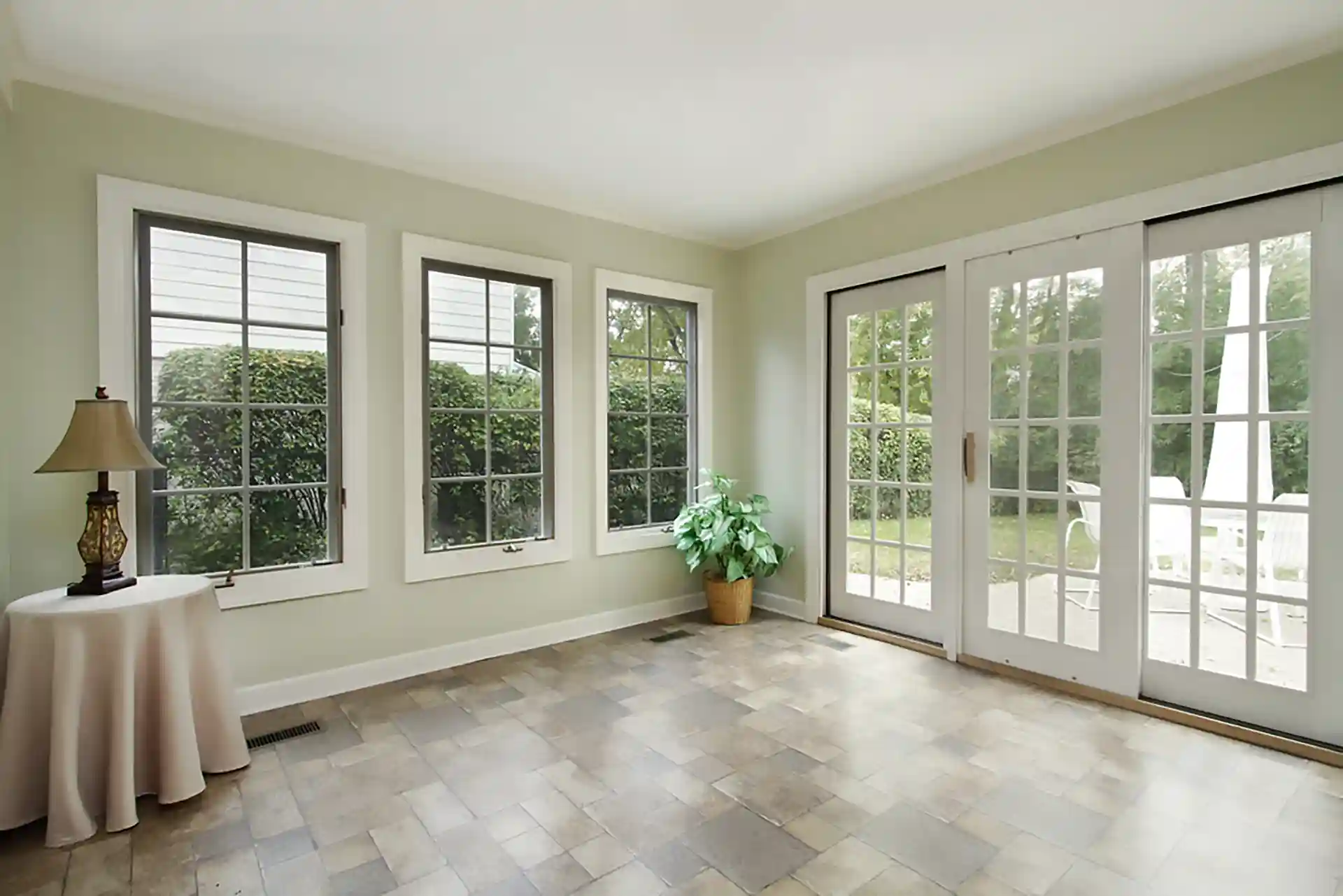 Bright sunroom with large windows, French doors, and a view of the backyard patio.
