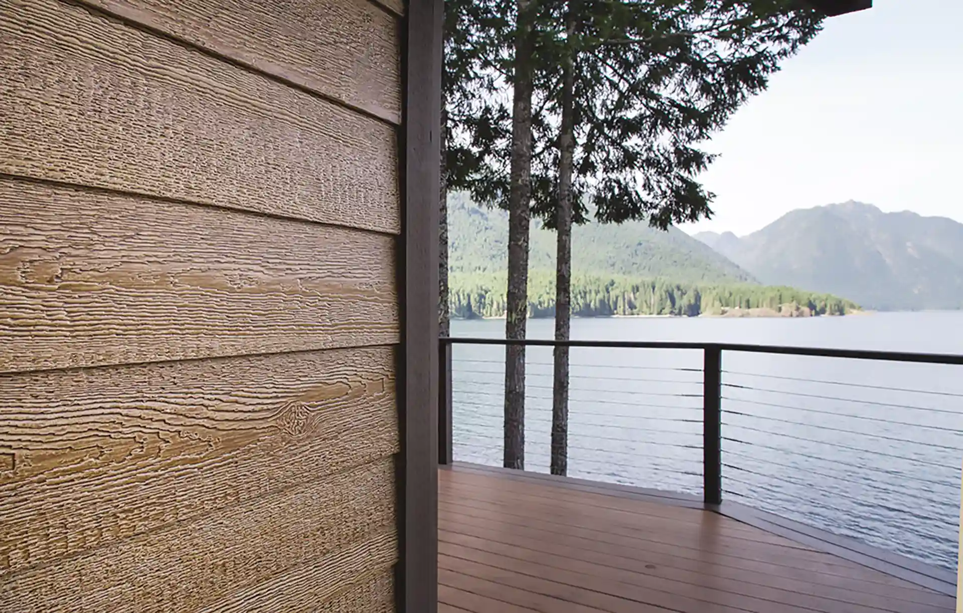 Lakeside deck with wood siding, cable railing, and mountain views. 