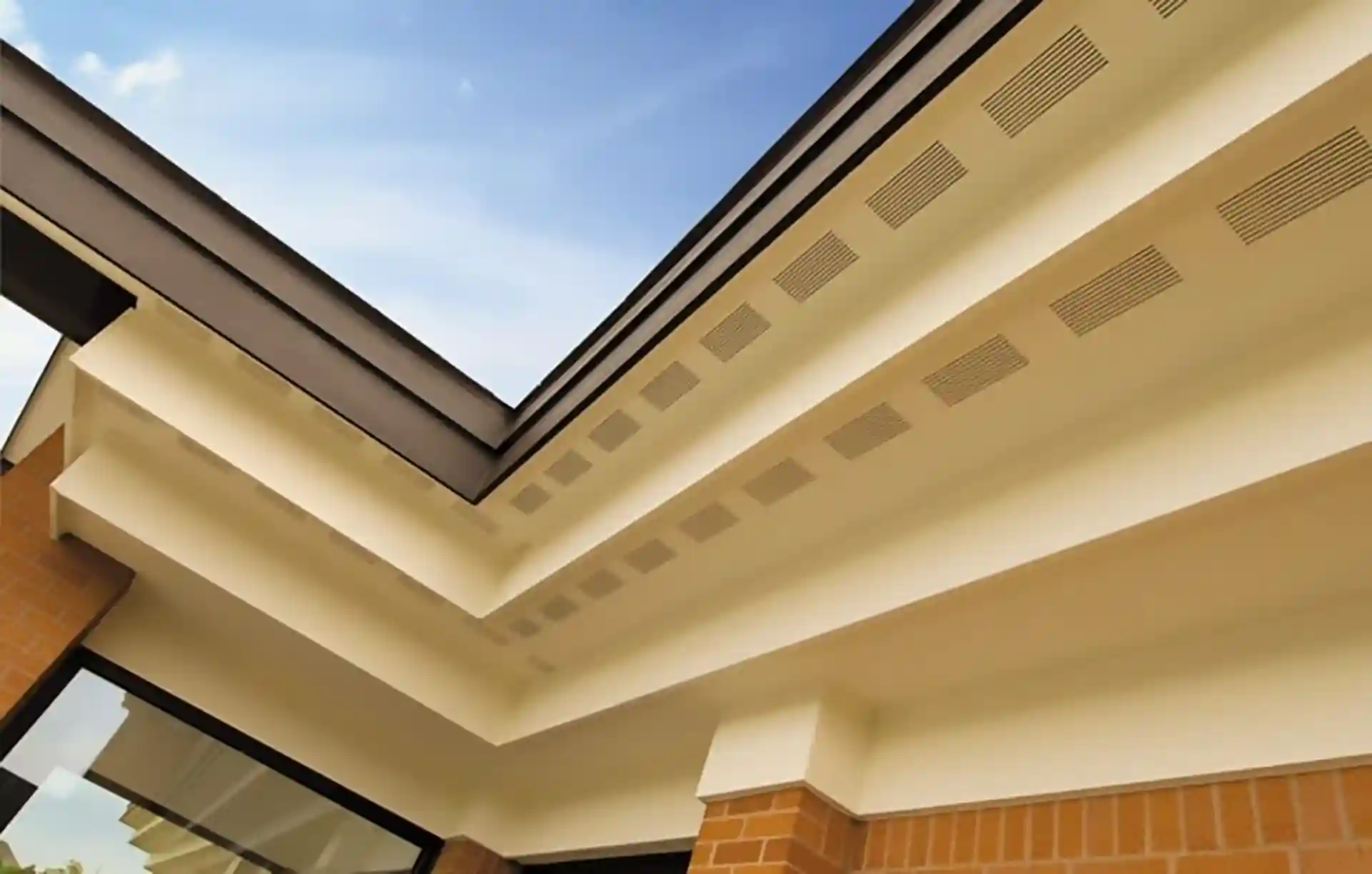 Close-up of a soffit and fascia system with vented panels on a modern building. 